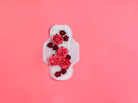 White sanitary pad with red and pink flowers on it, woman health or body positive concept. Pink background.  Flatlay. Copyspace