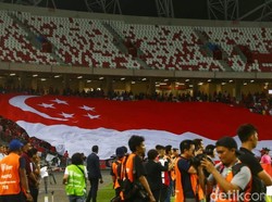 Suporter Singapura membentangkan bendera raksasa di tribun stadion.