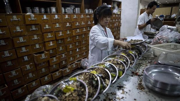 This picture taken on November 7, 2018 shows a woman mixing medicine in the pharmacy of the Yueyang Hospital, part of the Shanghai University of Traditional Chinese Medicine, in Shanghai. - With a history going back 2,400 years, traditional Chinese medicine (TCM) is deeply rooted in China and remains popular despite access to Western pharmaceuticals. Now the authorities are hoping to modernise and export the remedies, but they face major obstacles. (Photo by Johannes EISELE / AFP)