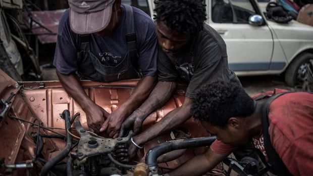 Young mechanics work on the engine of a Renault 4L  at Elyse Rakotondrakonona's workshop in Antananarivo's Antoamadikina neighbourhood, on November 06, 2018. - The iconic French car, in production between 1961 and 1992 and till 1994 in Slovenia, has an enduring appeal in Madagascar where mechanic like Elyse work wonders with the limited supply of spare parts available to them. (Photo by MARCO LONGARI / AFP)