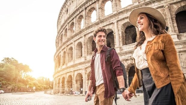 Young couple at the Colosseum, Rome - Happy tourists visiting italian famous landmarks
