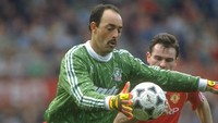 Kiper Liverpool, Bruce Grobbelaar, berupaya mengamankan gawangnya dari serbuan Brian McClair pada laga Liga Inggris di tahun 1990. (Ben Radford/Allsport)