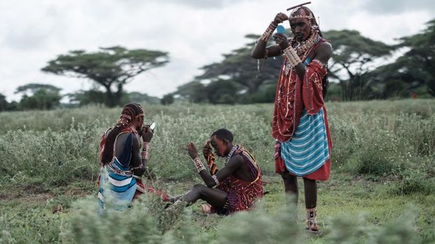 Maasai worriors prepares makeup before a sporting event dubbed the Maasai Olympics at Kimana, near Kenya's bordertown with Tanzania, on December 15, 2018. - The olympics are an initiative of international conservation groups led by Born Free, which have been held every two years since 2012 to offer Maasai warriors an alternative to killing lions as part of their traditional rite of passage. It was the brainchild of the wildlife charity Big Life Foundation and eight Maasai elders who wanted to ìstop lion hunting by our warriors once and for all. (Photo by Yasuyoshi CHIBA / AFP)