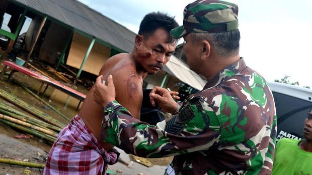 Korban bencana tsunami yang mengalami luka diperiksa aparat Bintara Pembina Desa (Babinsa) untuk diobati di Kampung Cikadu, Kecamatan Tanjung Lesung, Pandeglang, Banten, Minggu (23/12/2018). BPBD setempat melaporkan jumlah korban meninggal dunia 13 orang dan ratusan lainya mengalami luka-luka serta 400 lebih rumah warga di pinggir pantai roboh akibat terjangan gelombang tinggi Sabtu (22/12) malam. ANTARA FOTO/Muhammad Bagus Khoirunas/af/hp.