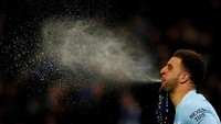 Bek kanan Manchester City Kyle Walker menyemburkan air yang baru saja diminumnya di tengah laga melawan Leicester City di Liga Inggris, Februari lalu. Pada akhirnya, City menang telak dengan skor 5-1. Foto: Jason Cairnduff/Action Images via Reuters