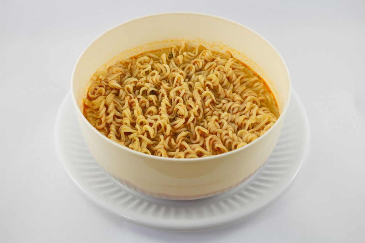 Instant noodle and spicy seasoning in white bowl with chopstick