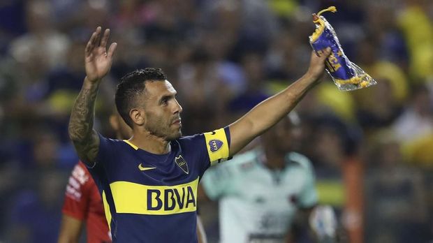 Pemain dengan Codet Unik Boca Juniors' Carlos Tevez (R) holds up the team standard after their Argentina First Division Superliga football match against Colon at La Bombonera stadium, in Buenos Aires, on January 27, 2018. - Carlos Tevez returned to Boca Juniors after cutting short a spell with Chinese Super League side Shanghai Shenhua. (Photo by Alejandro PAGNI / AFP)