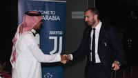 Kapten Juventus, Giorgio Chiellini, menyalami petugas bandara yang berpakaian khas Arab Saudi, bergamis putih dengan sorban merah putih. (Foto: Claudio Villa/Getty Images for Lega Serie A)