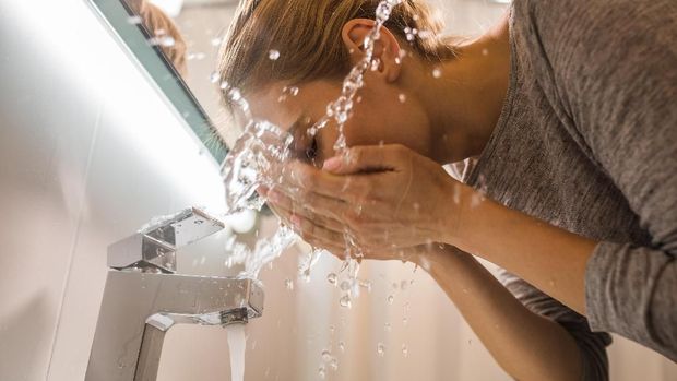 Below view of a woman washing her face in the bathroom.