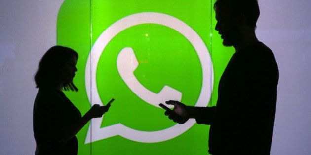 People are seen as silhouettes as they check mobile devices whilst standing against an illuminated wall bearing WhatsApp Inc's logo in this arranged photograph in London, U.K., on Tuesday, Jan. 5, 2016. WhatsApp Inc. offers a cross-platform mobile messaging application that allows users to exchange messages. Photographer: Chris Ratcliffe/Bloomberg via Getty Images
