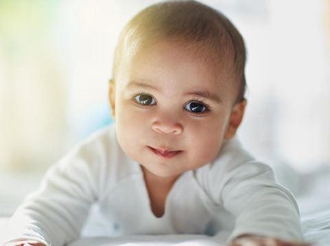 Cute little baby boy with handmade knitted cloths, playing with little teddy bear toy, smiling at camera
