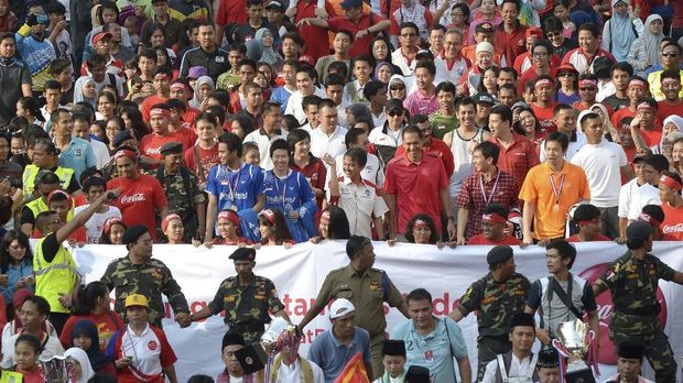 Indonesian men's doubles shuttlers Mohammad Ahsan and Hendra Setiawan (pair at centre L-in blue) and players Tontowi Ahmad and Liliyana Natsir (centre R-in red and orange) walk with the chief of the Indonesian Badminton Association (PBSI) and Trade Minister Gita Wirjawan (4th R-in red) and Indonesia's Sport Minister Roy Suryo (5th R-in red and white) during a parade in Jakarta on August 18, 2013 to celebrate Indonesia's victories in the badminton World Championships in China last week. Two pairs of Indonesian shuttlers, mixed doubles partners Tontowi Ahmad and Liliyana Natsir and the men's doubles pair Mohammad Ahsan and Hendra Setiawan, brought home two titles from the 2013 World Championships that took place in Guanzghou, China from August 4 to 11.       AFP PHOTO / ADEK BERRY (Photo by ADEK BERRY / AFP)