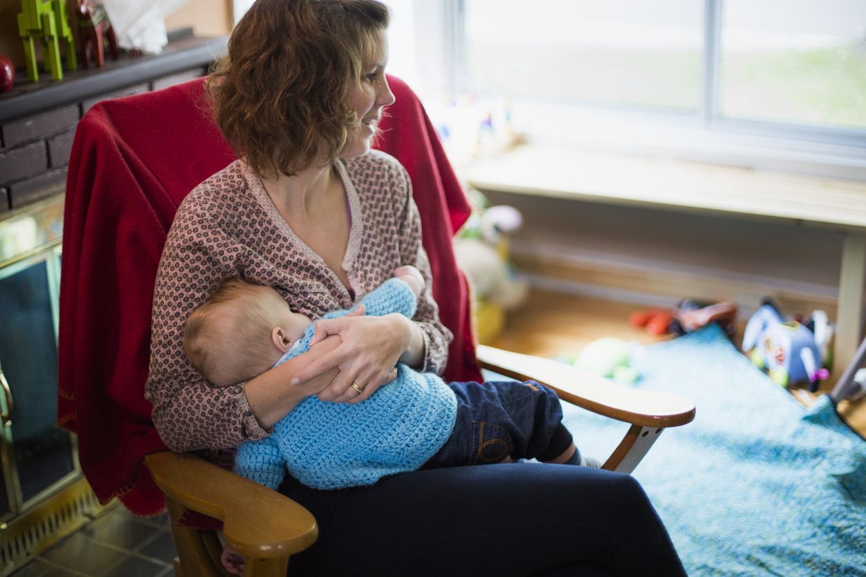 Mom breastfeeds her baby at home