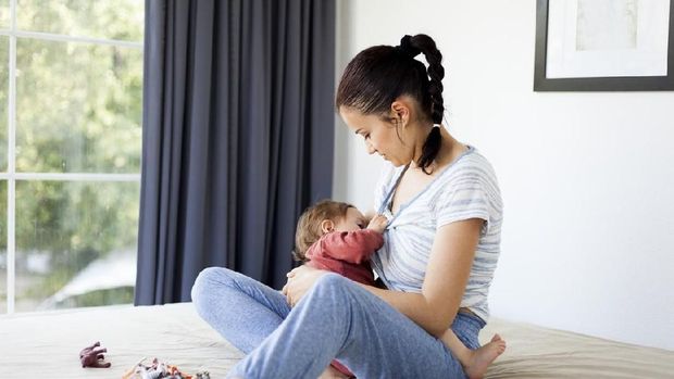 Mom breastfeeds her baby at home