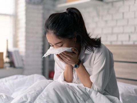 The businessman is unable to work, she is sick and sneezing heavily in bed.