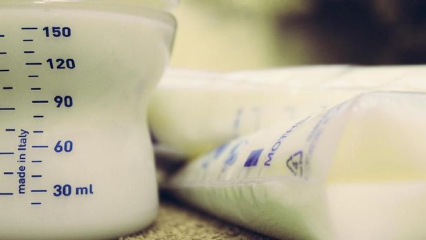 baby bottle filed with breast milk and storage bags with frozen breastmilk, breastfeeding concept
