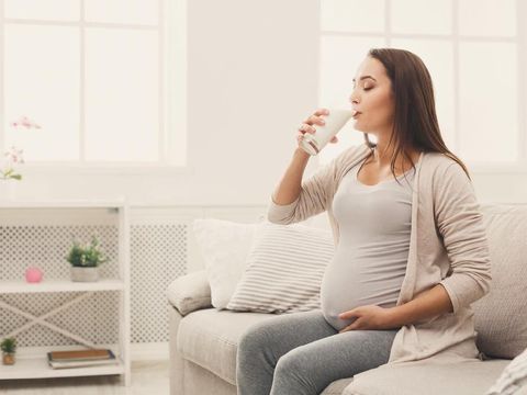 Pregnant woman drinking glass of milk copy space. Young expectant lady enjoying healthy drink. Healthcare, nutrition, vitamins, pregnancy concept