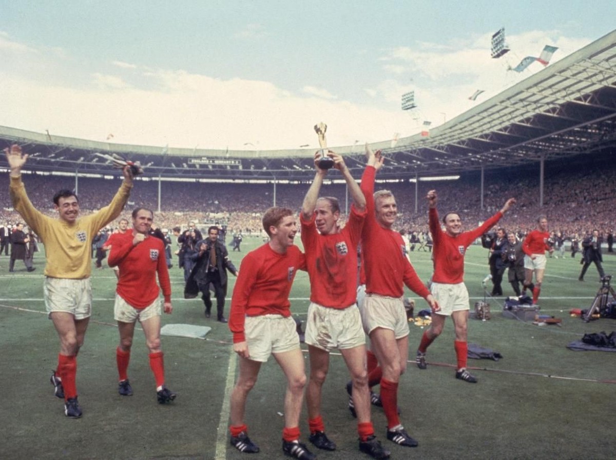 Bobby Charlton mengangkat trofi Jules Rimet 1966 bersama penggawa Timnas Inggris dan Gordon Banks mengikuti di belakang (Hulton Archive/Getty Images)