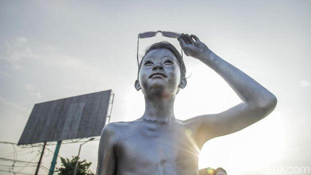 A number of teenagers who paint their whole body with silver color earn money by entertaining motorists in the Kalimalang area, Bekasi.  Here's the action.