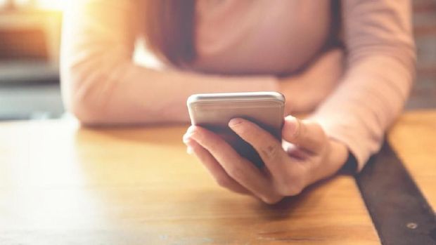 Closeup of thoughtful young Asian woman holding mobile phone and surfing Internet. Attractive student taking selfie at cafe. Communication and work balance concept