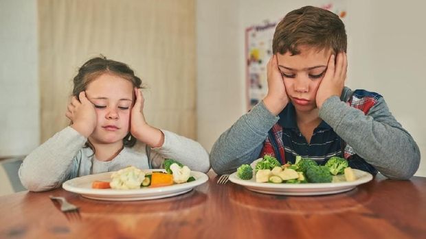 Cropped shot of two grumpy children refusing to eat their vegetables