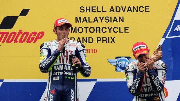 Spanish rider Jorge Lorenzo (R) of Fiat Yamaha team kisses his trophy next to team mate Valentino Rossi on the podium of the Malaysian Grand Prix at Sepang on October 10, 2010. Lorenzo claimed his first world MotoGP crown after finishing third in the Malaysian Grand Prix while team-mate Valentino Rossi won the race with a brilliant performace.  AFP PHOTO / SAEED KHAN (Photo by SAEED KHAN / AFP)