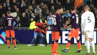 Laga sendiri sempat terinterupsi karena ada penonton yang menerobos ke lapangan. Petugas lapangan berusaha mengamankannya. (Foto: Marc Atkins/Getty Images)