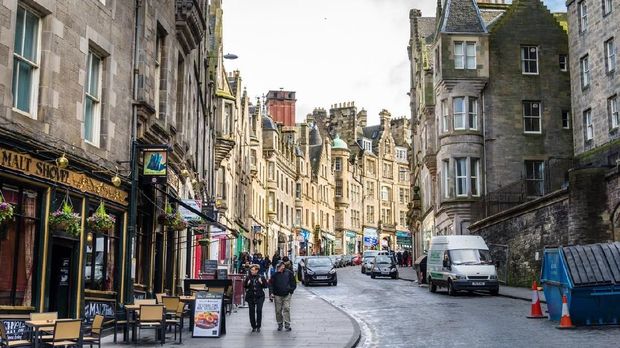 Edinburg, UK - March 28, 2015: Locals and Tourists Strolling along Cockburn Street in Old Town on a cloudy winter day. Cockburn Street is a picturesque street created as a serpentine link from the Royal Mile to Waverley Station in 1856 in Edinburgh's city centre.