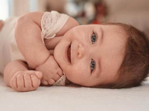 cute baby girl having fun and laughing, lying on side. lifestyle shot.