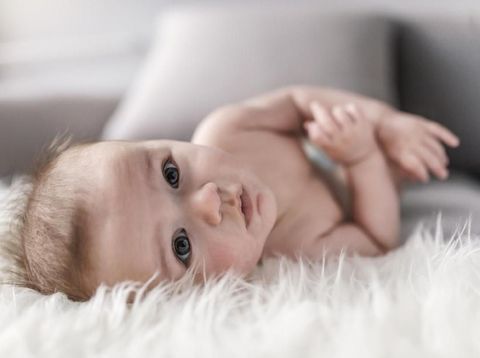bayi laki-laki Close up portrait of infant lying on white fluffy bed indoors. Photo of the boy at the age of four months. Baby boy wearing diaper in white sunny bedroom. Newborn child relaxing in bed. Nursery for children. Textile and bedding for kids. Family morning at home. New born kid during side time looking at the camera.