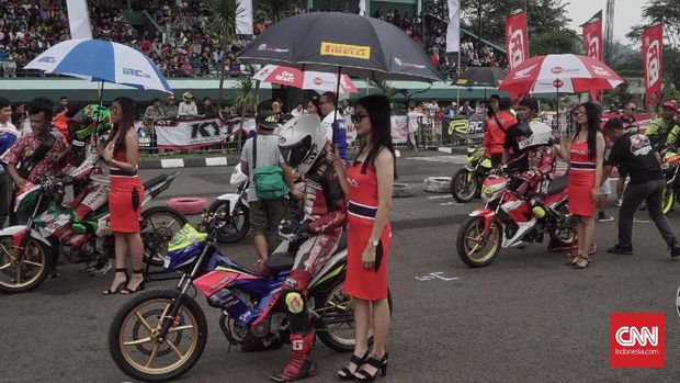 Gadis payung turut memeriahkan gelaran balap jalanan atau road race di Sirkuit Brigif Cimahi pada 13 Januari 2019.