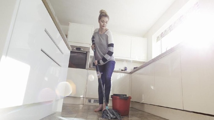Mengepel lantai One woman mopping the floor in her kitchen.