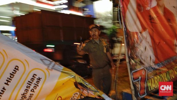 Petugas Satpol PP membersihkan baliho caleg-caleg.