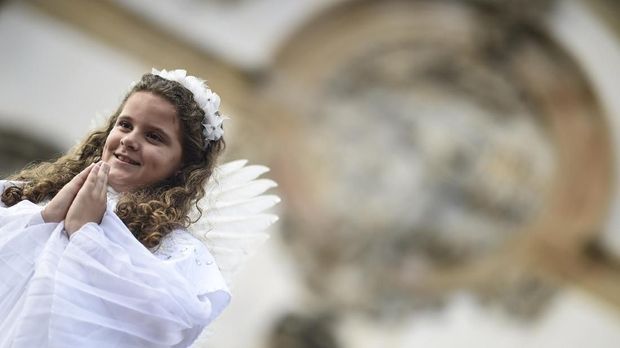 A girl dressed as an angel walks over a sawdust rug during an Easter procession representing the resurrection of Christ, in the Brazilian historic city of Ouro Preto, Minas Gerais State, on April 21, 2019. - The streets are decorated by locals and tourists who use about 60 tons of coloured sawdust. (Photo by Douglas MAGNO / AFP)