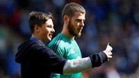 Meski sedang dirundung kekecewaan, kiper MU, David De Gea, tetap memberi kesempatan salah seroang fans untuk selfie. (Foto: Jason Cairnduff/Action Images via Reuters)