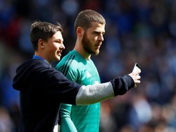 Meski sedang dirundung kekecewaan, kiper MU, David De Gea, tetap memberi kesempatan salah seroang fans untuk selfie. (Foto: Jason Cairnduff/Action Images via Reuters)