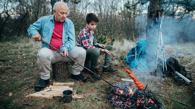 Photo of grandfather and grandson preparation barbecue in nature
