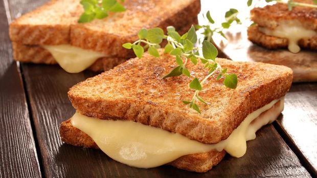 Fresh toast with cheese and herbs on wooden background