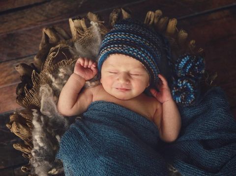 A newborn baby smiles in his sleep. He is ten days old.