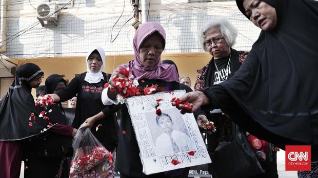 Keluarga korban menyiapkan bunga beserta foto anggota keluarganya yang sudah tiada.