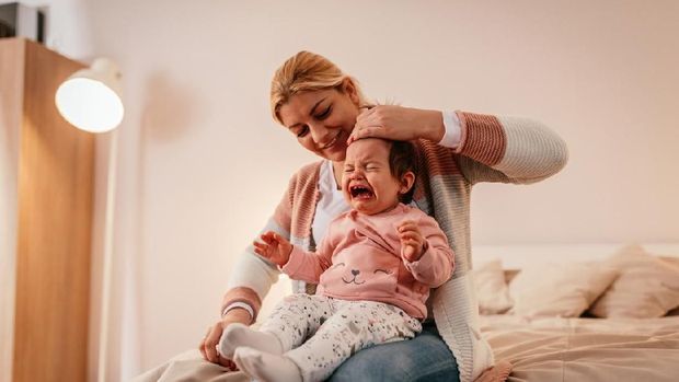 Mother holding a crying baby girl