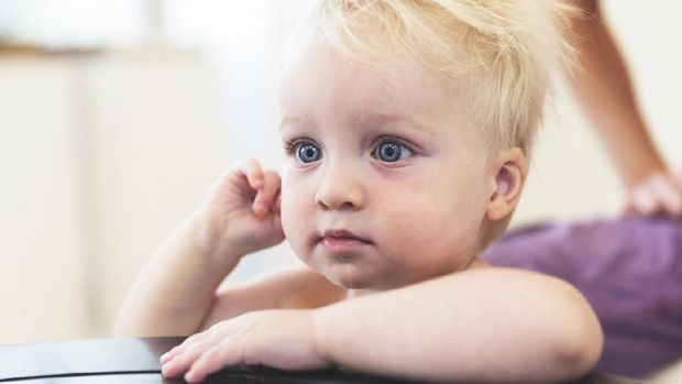 Single father working on his laptop as his baby boy observes, watches and happily sits near him.