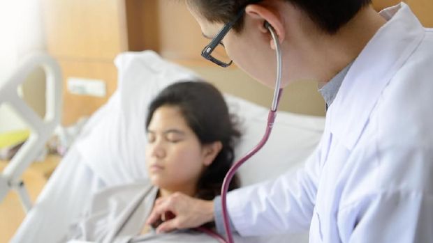 Asian female doctor examines a patient with a stethoscope