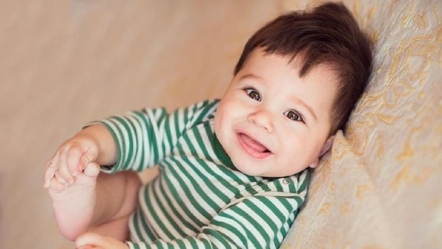 Portrait of happy beautiful baby on the bed in his room.