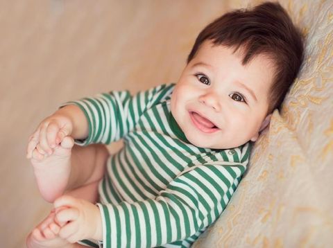 Portrait of happy beautiful baby on the bed in his room.