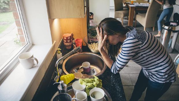 Upset mother with hands on head among mischievous little girls