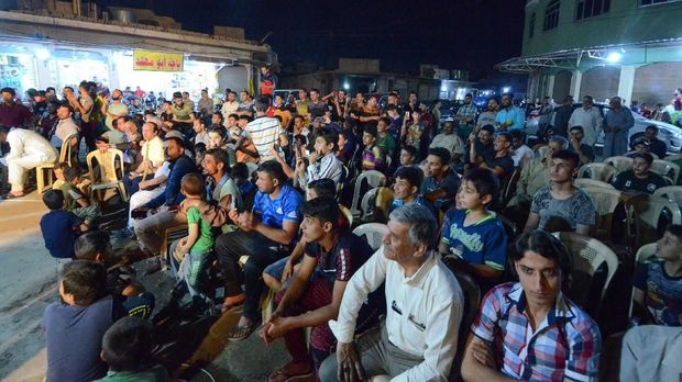 Masyarakat menyaksikan Abdel Wahed mendongeng di Mosul usai menjalani ibadah tarawih.