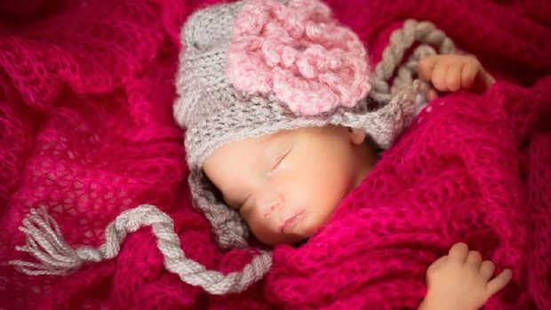 Newborn baby girl wearing a knitted baby hat.