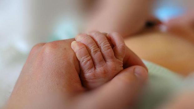 Newborn baby little hand hold by adult man hand of his father