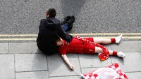 Bersandar di pangkuan ayah. Pendukung cilik Liverpool ini mengenakan pakian lengkap juga sambil membawa atribut bendera. (Foto: Jason Cairnduff/Action Images via Reuters)